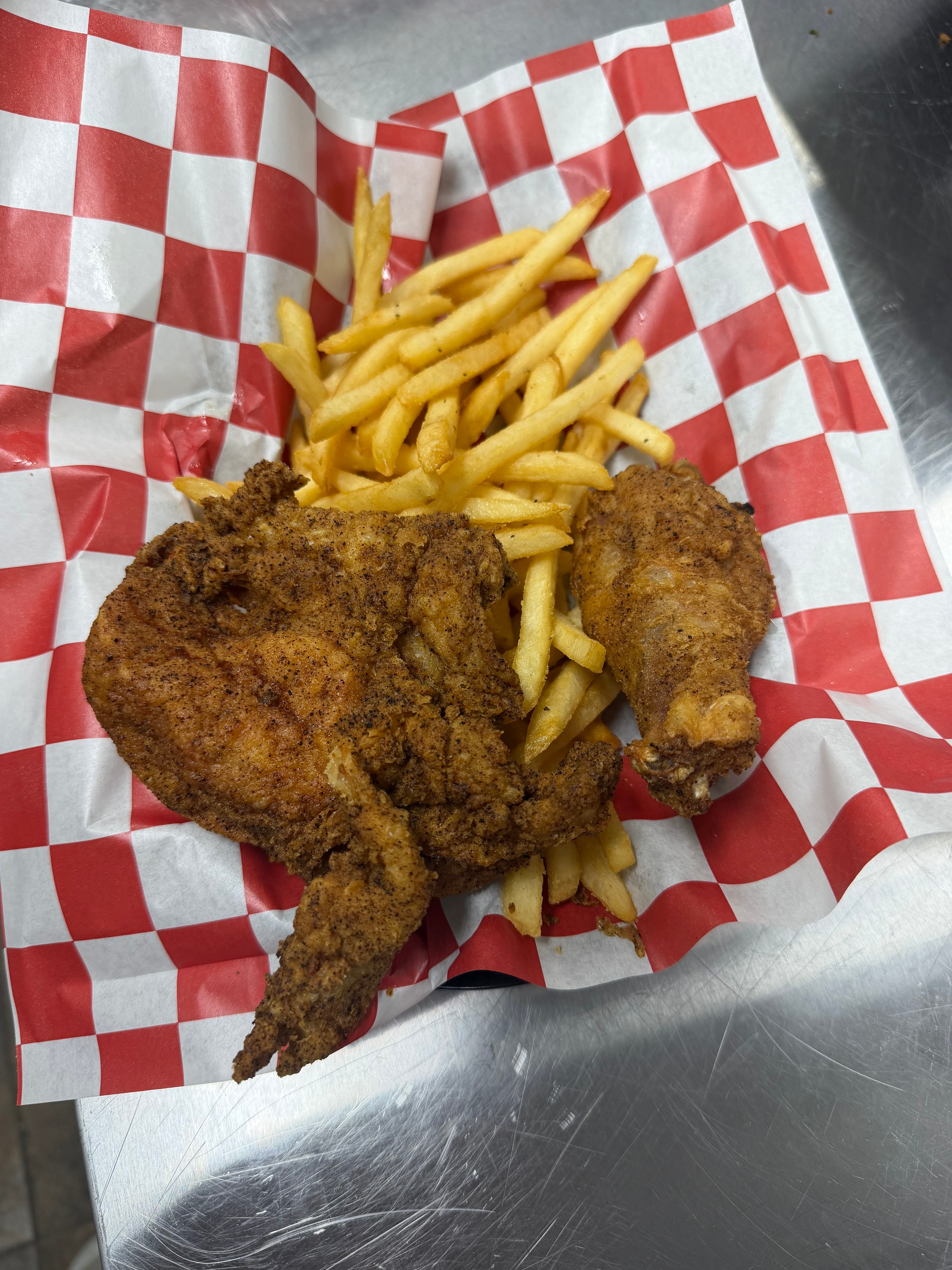 Broasted chicken with fries on checkered paper at Nina's