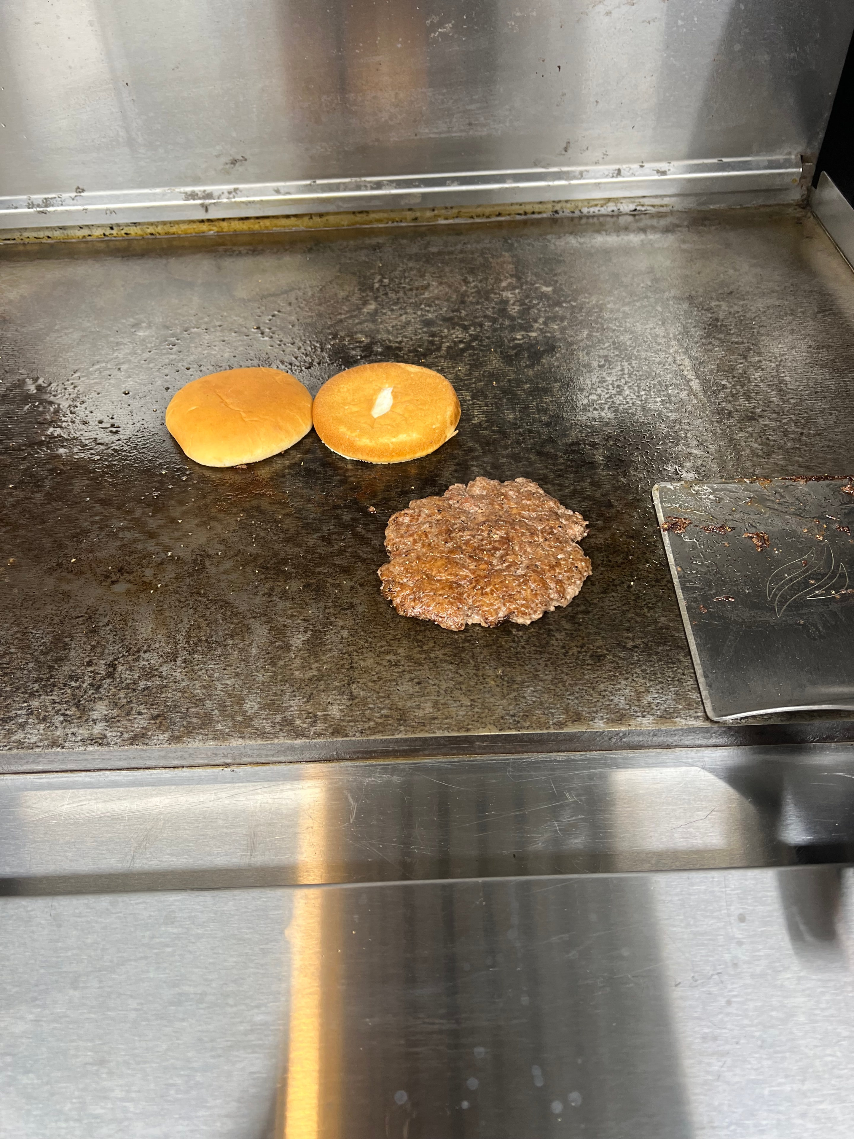 Burger patty on the griddle at Nina's kitchen
